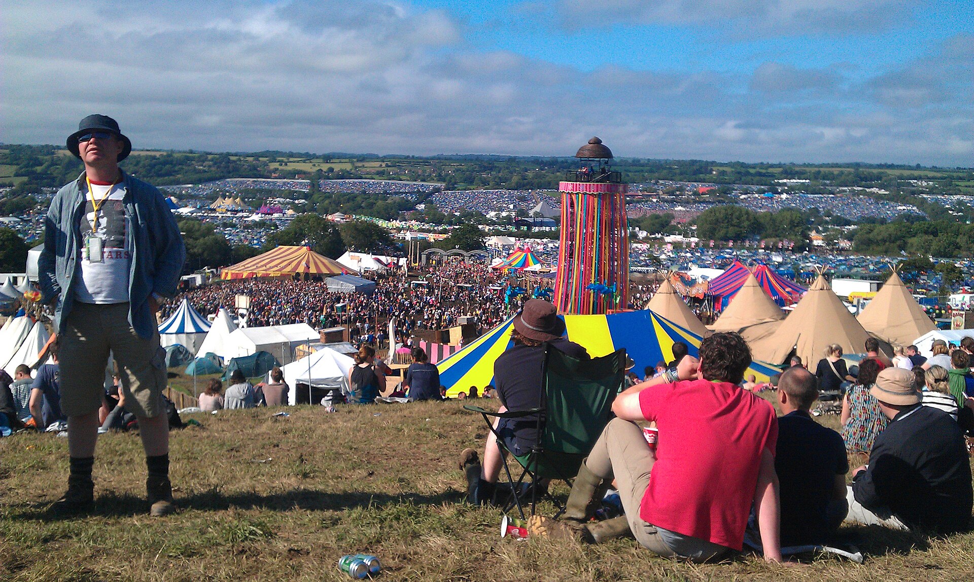 Festival crowd at Glastonbury with the Pyramid Stage lit up at dusk